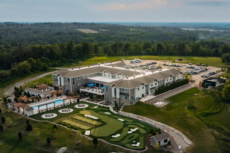 Aerial view of Skaneateles Fields Resort & Spa with outdoor pool, putting green, bocce courts, and surrounding grounds.